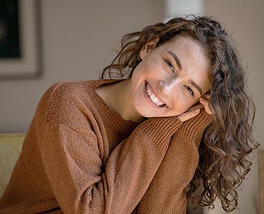 Jeune femme souriante qui se tient la tête