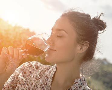 Femme dégustant un verre de vin rouge dans une vigne