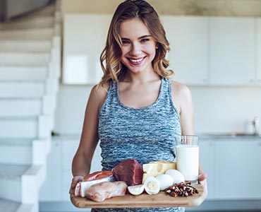 Jeune femme qui tient un plateau avec des aliments riches en protéines