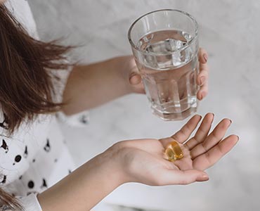 Jeune femme tenant une pilulle de vitamine D