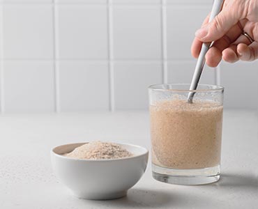 Psyllium blond mélangé dans un verre d'eau