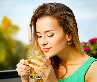 Jeune femme sirontant une tasse de thé vert