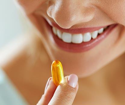 Jeune femme tenant une capsule d'omega 3